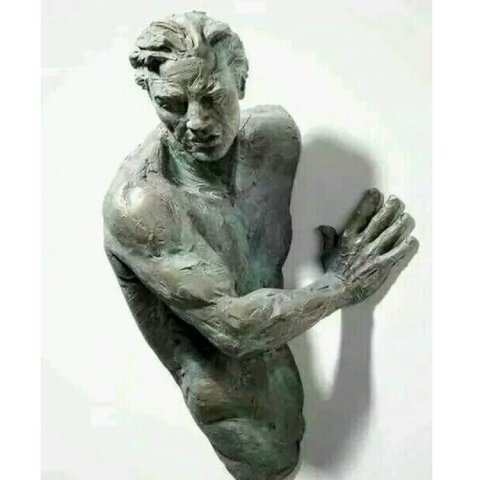 man coming out of wall sculpture