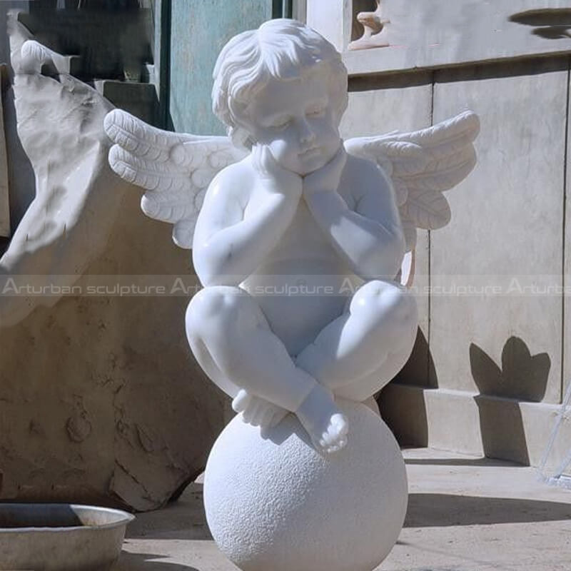 outdoor cherub sitting on ball statues