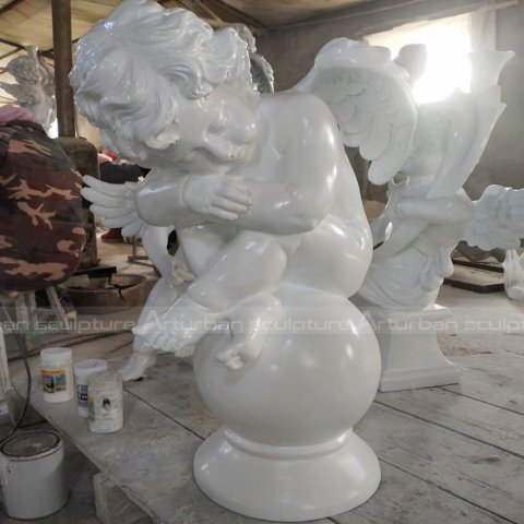 cherub on ball garden statue