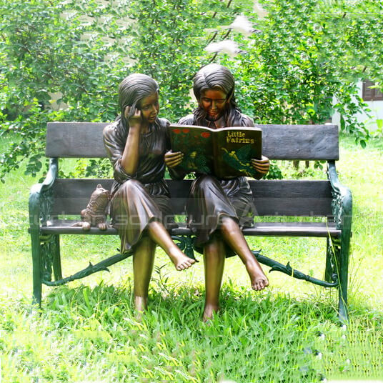 girl reading book on bench statue